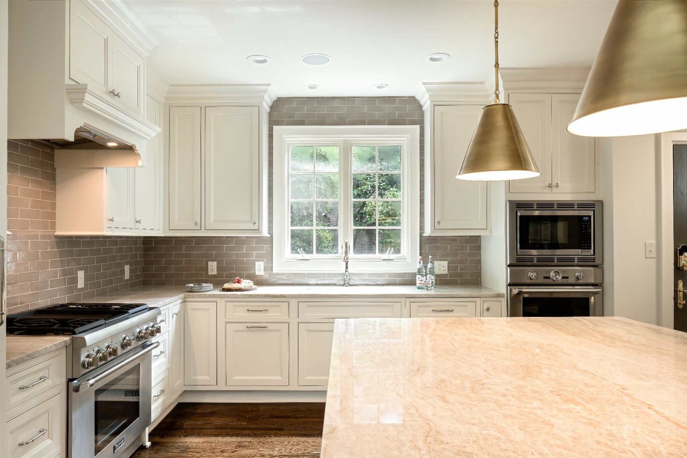 Cream kitchen with brass pendants over the island and a large window over the sink