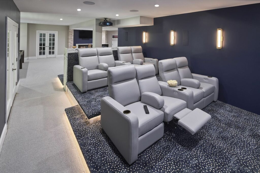 Basement movie room with LED lighting and comfy recliner chairs.