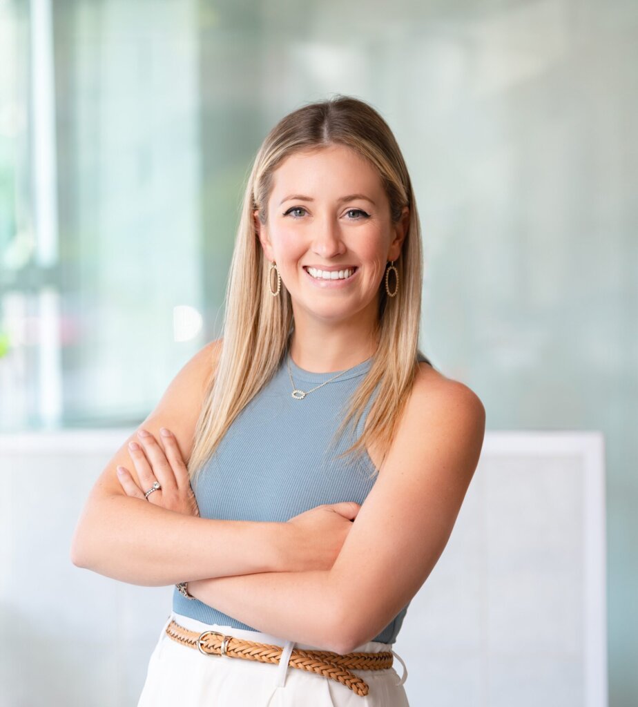a headshot of a woman named Darian who has blonde hair and is wearing a blue tank top and white pants