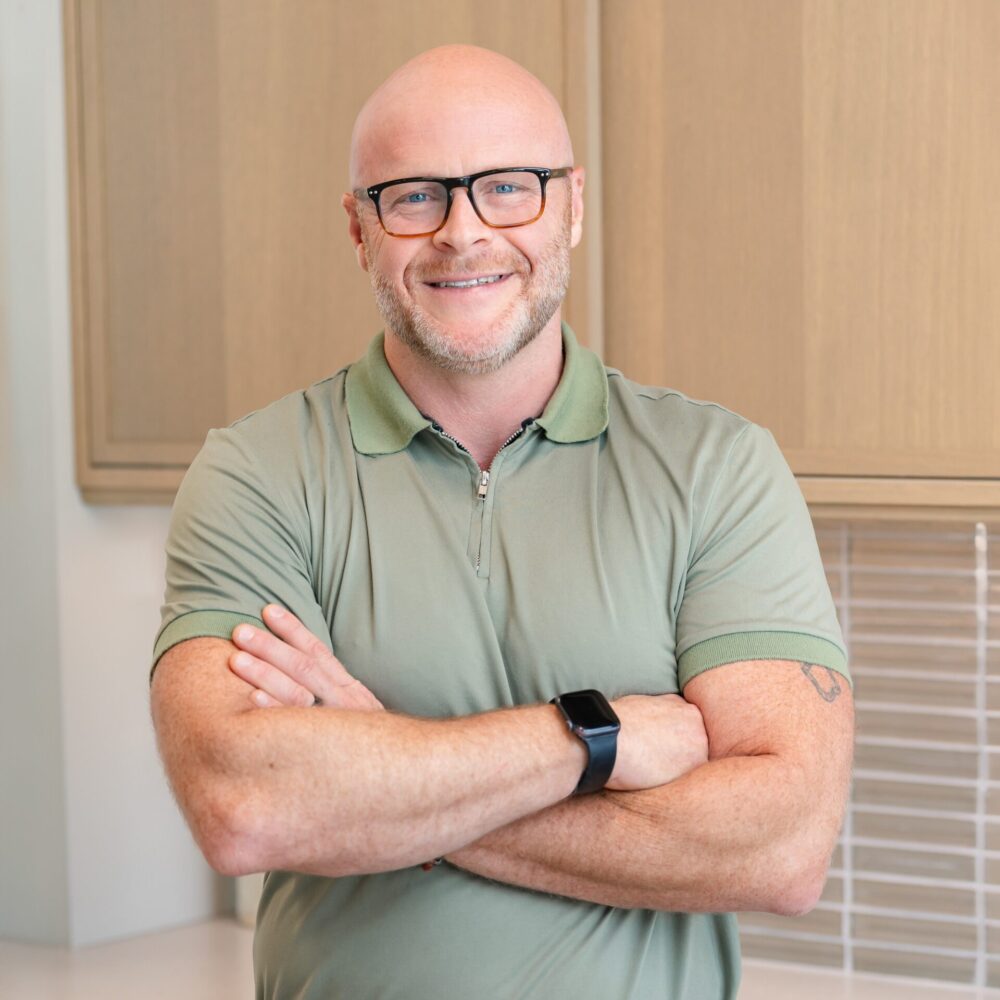 a headshot of a man named Henry who is wearing dark glasses and a green collared shirt