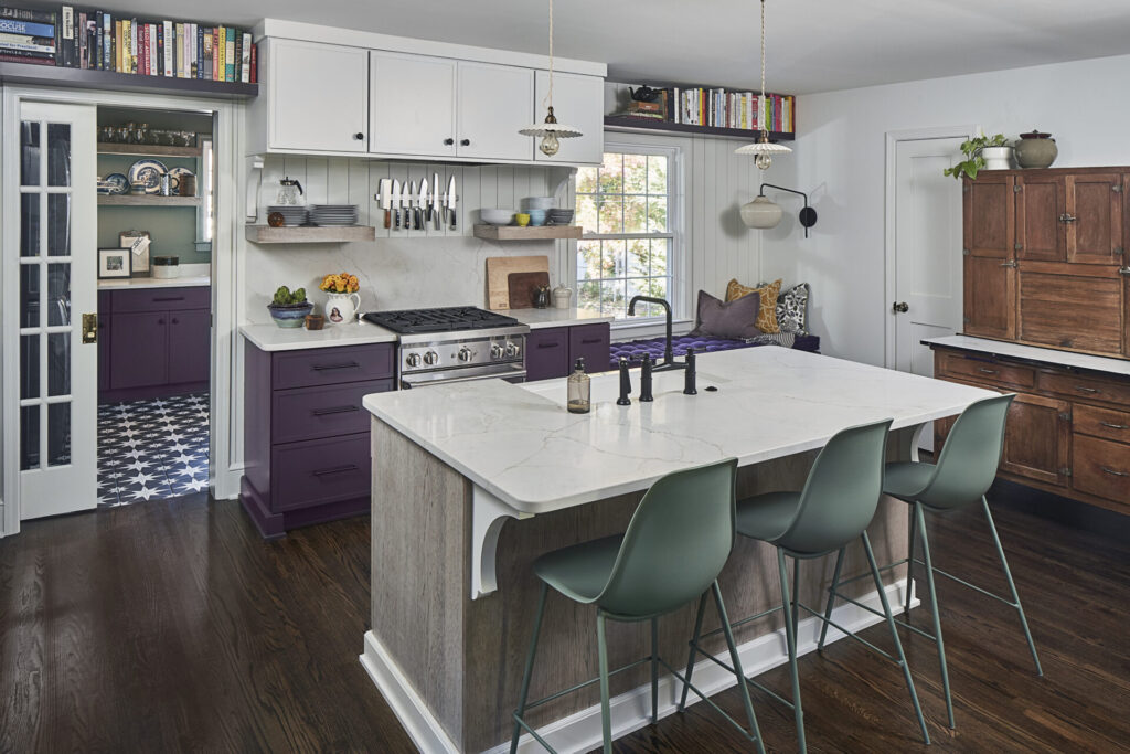 A charming bungalow style kitchen with warm earthy tones that cover the island base and lower cabinetry, complemented by vintage-inspired wallpaper.