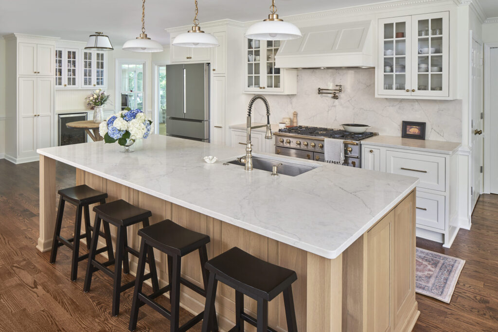 The kitchen features alabaster-painted cabinets and a rift-cut white oak island. Quartz countertops with soft veining extend to the backsplash. Unlacquered brass hardware and polished nickel plumbing add a touch of elegance.