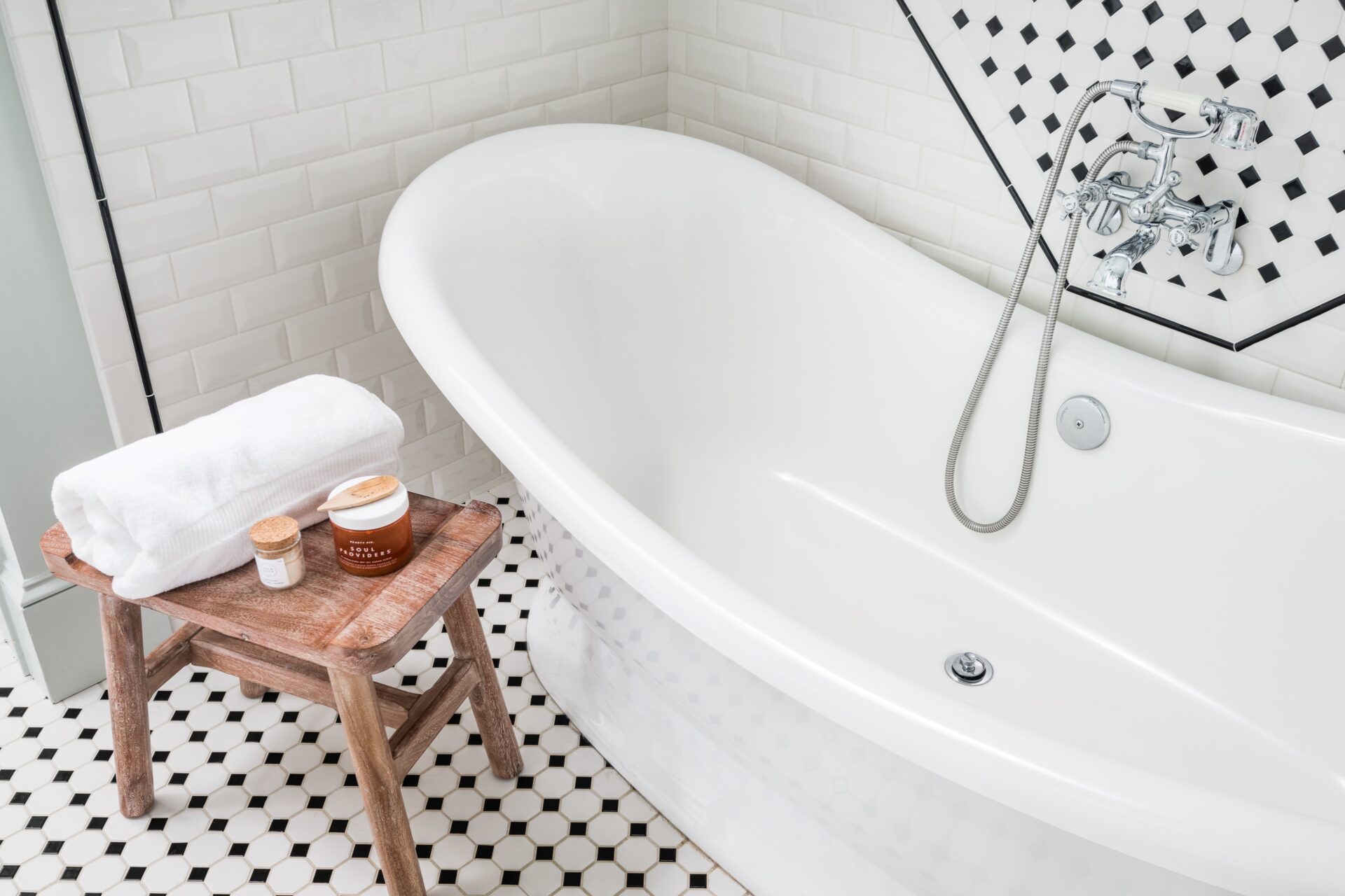 Minimalist bathroom featuring a unique tile floor design, a sleek bathtub, wooden bench, showcasing clean lines and a modern aesthetic.