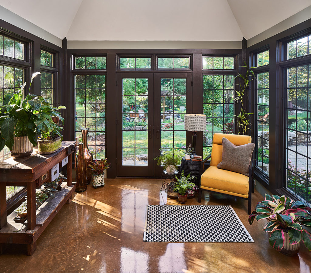 Sunroom full of natural light, concrete floors, and panoramic views of the backyard