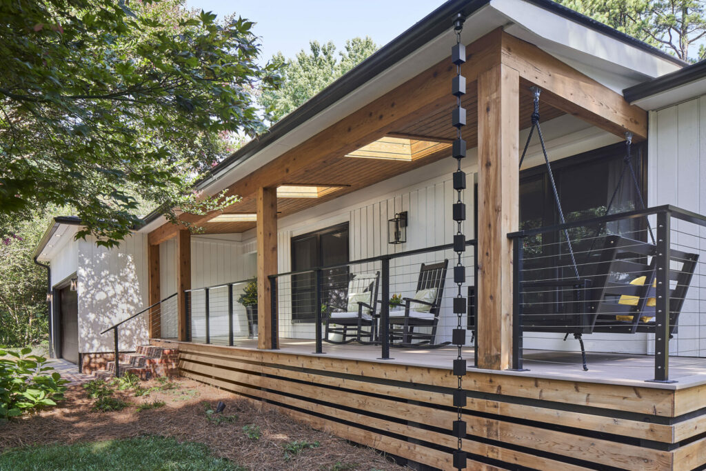 Modern front porch with wood posts, skylights, a porch swing, and black cable railing, blending natural and contemporary design elements.