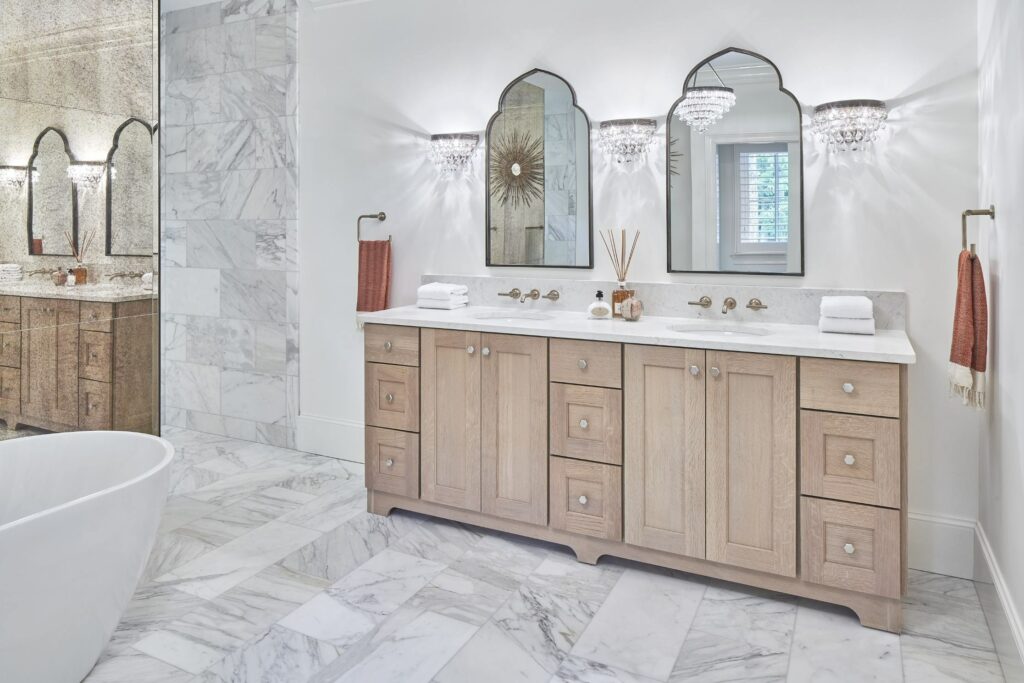 Traditional primary bath with a double white oak vanity and brushed bronze fixtures