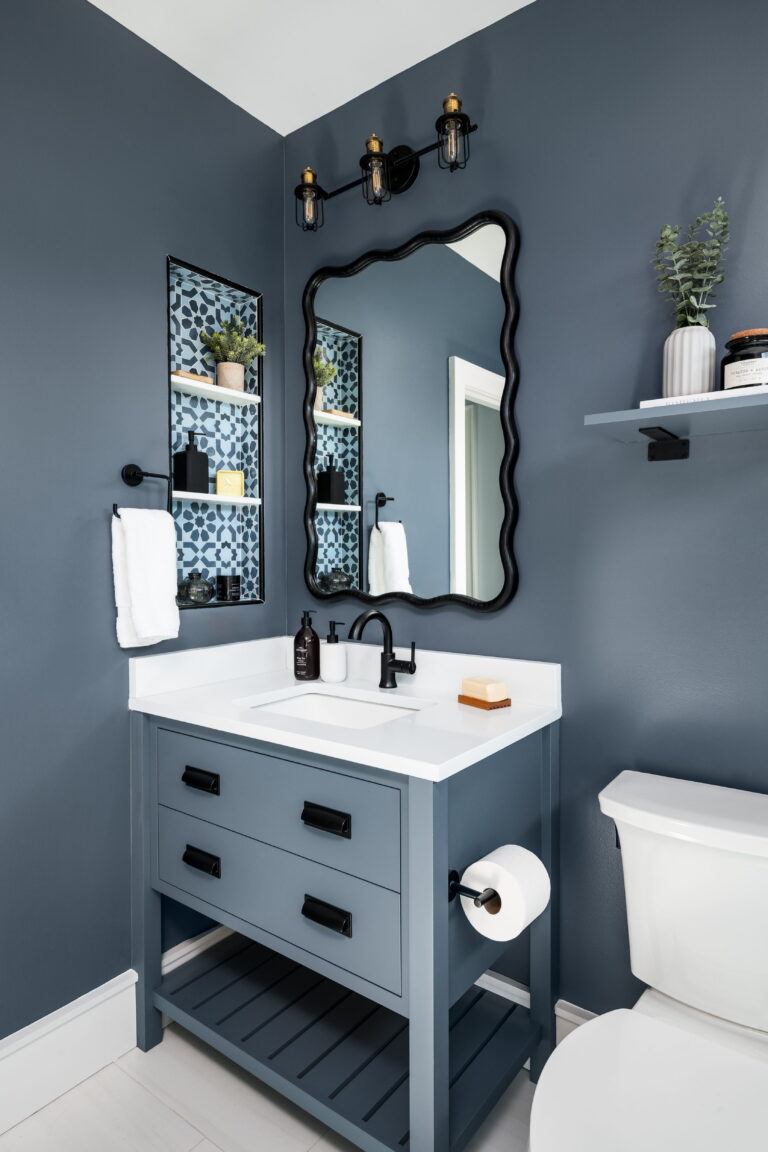 blue bathroom vanity with a slatted bottom and wavy mirror