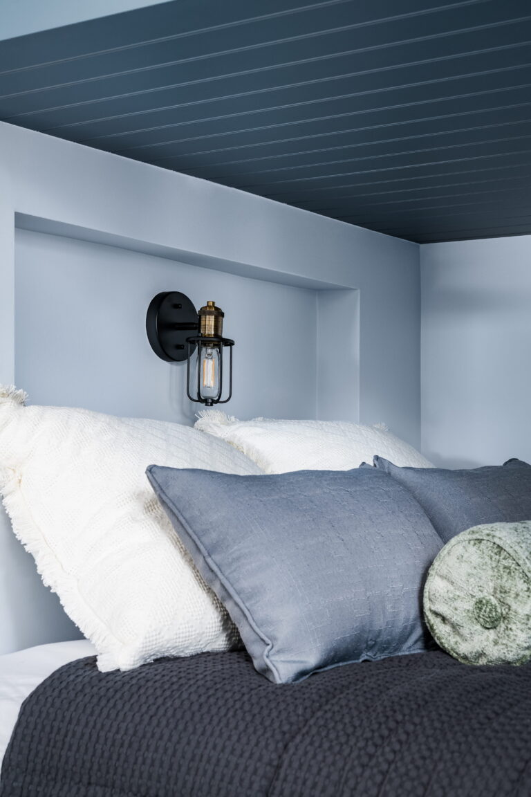 recessed niche with wall sconce at the head of a bunk bed